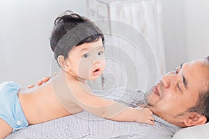 Selective focus happy father playing with 1-2 months newborn baby with love on bed at home, Asian dad and adorable infant have fun