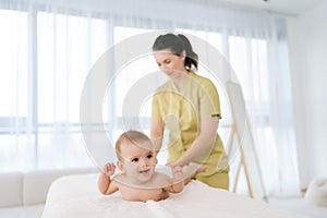 Selective focus of happy smiling infant boy having legs massage. Female doctor doing gymnastics and foot massage to