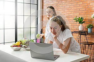 Selective Focus on Healthy women in a white bathrobe using laptop to find a vegetarian diet food recipe, ordering food online from