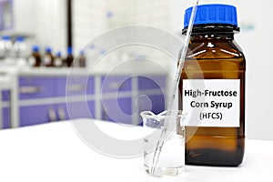 Selective focus of high-fructose corn syrup or hfcs food and beverage sweetener in dark brown glass bottle inside a laboratory.