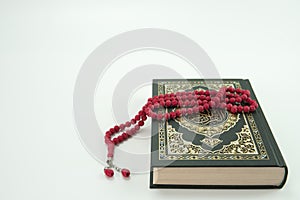 Al Quran and red tasbih or rosary beads over white background. photo