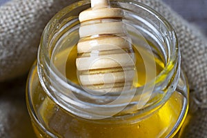 Selective focus. honey flows from Honey Dipper, into a jar of honey. jar in a sackcloth bag