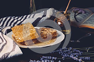 selective focus of honeycombs on plate lavender and jar with honey stick