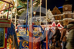 Selective focus at horse carousel and background of night atmosphere of Christmas market.