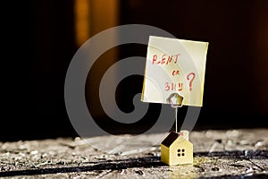 Selective focus of house model,poster , yellow sticker with notes written with `BUY OR RENT `. Real estate theme.Text