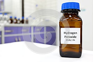 Selective focus of hydrogen peroxide solution in brown amber bottle. Blur laboratory background with copy space. photo