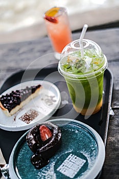 Selective focus of ice matcha green tea and cake on wooden plate. Drink that is sugar-free and homemade Food and baverage