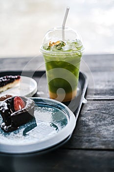 Selective focus of ice matcha green tea and cake on wooden plate. Drink that is sugar-free and homemade Food and baverage