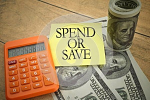 Selective focus image of calculator and bank note with SPEND OR SAVE wording on a wooden background.Business and economy concept