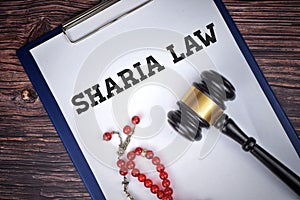 Selective focus image of gavel and beads with Sharia Law wording on a wooden background. Sharia Law concept