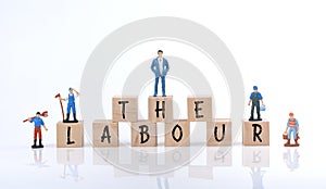 Selective focus image of group of miniature people and wooden block with Labor Day wording. Labor Day concept