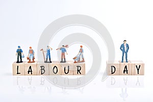 Selective focus image of group of miniature people and wooden block with Labor Day wording. Labor Day concept