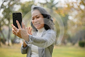selective focus image, Happy 60s aged Asian woman is taking a selfie with her smartphone