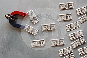 Selective focus image of miniature businessman attracts money using magnet