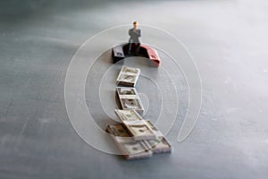 Selective focus image of miniature businessman attracts money using magnet