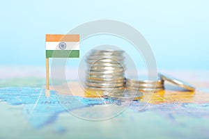 Selective focus of Indian flag in blurry world map with coins. India economy and wealth concept.