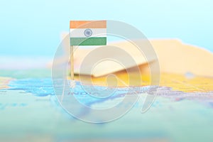 Selective focus of Indian flag in blurry world map and wooden airplane model. India as travel and tourism destination concept.