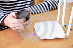 Selective focus at internet router with man using smart phone device to connect to internet or wireless connection at home, High s