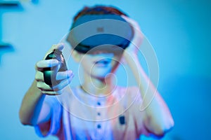 Selective focus on joystick, Young kid playing video game by wearing vr or virtual reality headset using game pad or