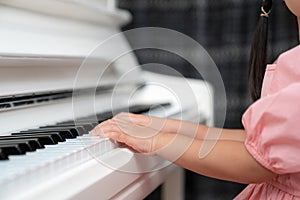 Selective focus on the kid finger playing grand piano. Teacher or instructor teach a girl on the class play melody. Close up hand