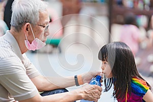 Selective focus kid. Grandfather hold water bottle for granddaughter to drink to quench  thirst.