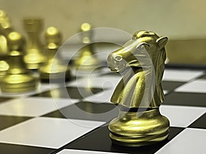 In selective focus of Knight,Chess piece in gold color put on board game