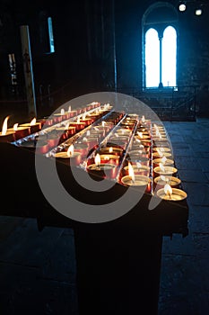 Selective focus on lit candles in perspective contrast between dark and light from window