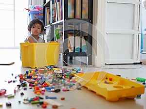Selective focus of a little Asian baby girl searching a box of toys and spreding them all over the floor