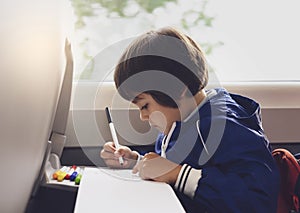 Selective focus of little boy draws with coloured pen on white paper, Kid traveling by the train, Little boy in a high speed expre