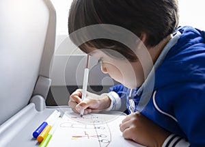 Selective focus of little boy draws with coloured pen on white paper, Kid traveling by the train, Little boy in a high speed expre