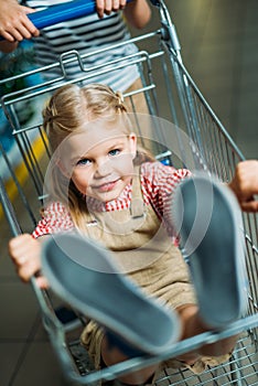 selective focus of little girl sitting in shopping cart photo