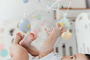 Selective Focus, A Little Hand of Adorable Baby Boy Enjoy Playing with Crib Mobile in Home Playpen