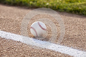 Selective focus low angle view of a baseball on gravel infield near stripe and grass