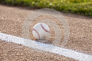 Selective focus low angle view of a baseball on gravel infield near stripe and grass photo