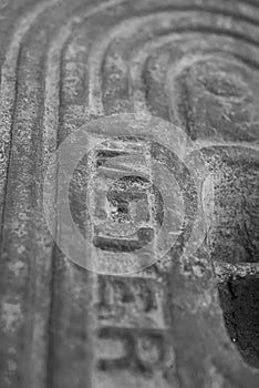 A black and white macro detail of an old steel water meter cover dug out of the ground photo