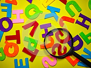 Selective focus.Magnifying glass and colorful word on yellow background.Education concept.Shot were noise and film grain.