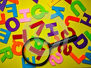 Selective focus.Magnifying glass and colorful word on yellow background.Education concept.Shot were noise and film grain.