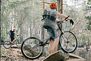 selective focus of male extreme cyclist on mountain bike talking to friend with bmx