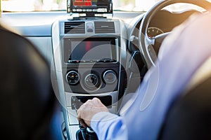 Selective focus of man driving and change gear a car. View from inside the taxi car