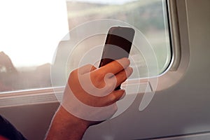 Selective focus of man hand with smart phone which he is  a Freelancer as  working  by moblephone in the train -Trip travel and