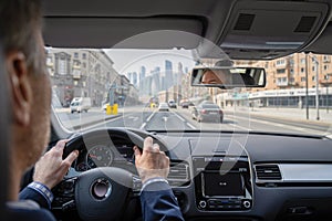 Selective focus of man hands on steering wheel driving a car on the speed highway. View from above. Moscow. Russia.