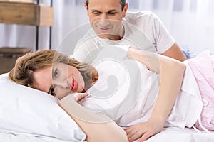 selective focus of man looking at smiling wife lying near