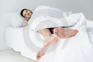 selective focus of man sleeping on bed, feet