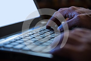 Selective focus on man two hand typing laptop/PC/computer keyboard in night dark tone low key