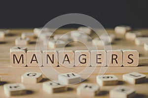 Focus of managers inscription on cubes surrounded by blocks with letters on wooden surface isolated on black photo