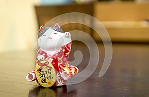 Selective focus Maneki Neko, Japanese lucky cat, on a Wooden table with blurred background.