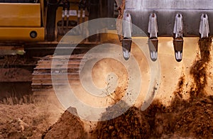 Selective focus on metal bucket teeth of backhoe digging soil. Backhoe working by digging soil at construction site. Crawler