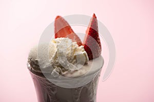 Selective focus of milkshake with ice cream and strawberry halves