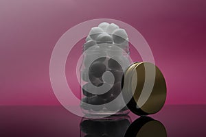 Mothball inside jar isolated in pink background.