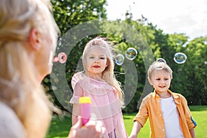 selective focus on mother blowing soap bubbles while spending time with kids